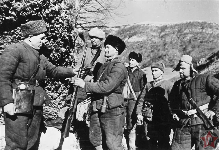 Командир отряда сопротивления вручает бойцу боевой карабин